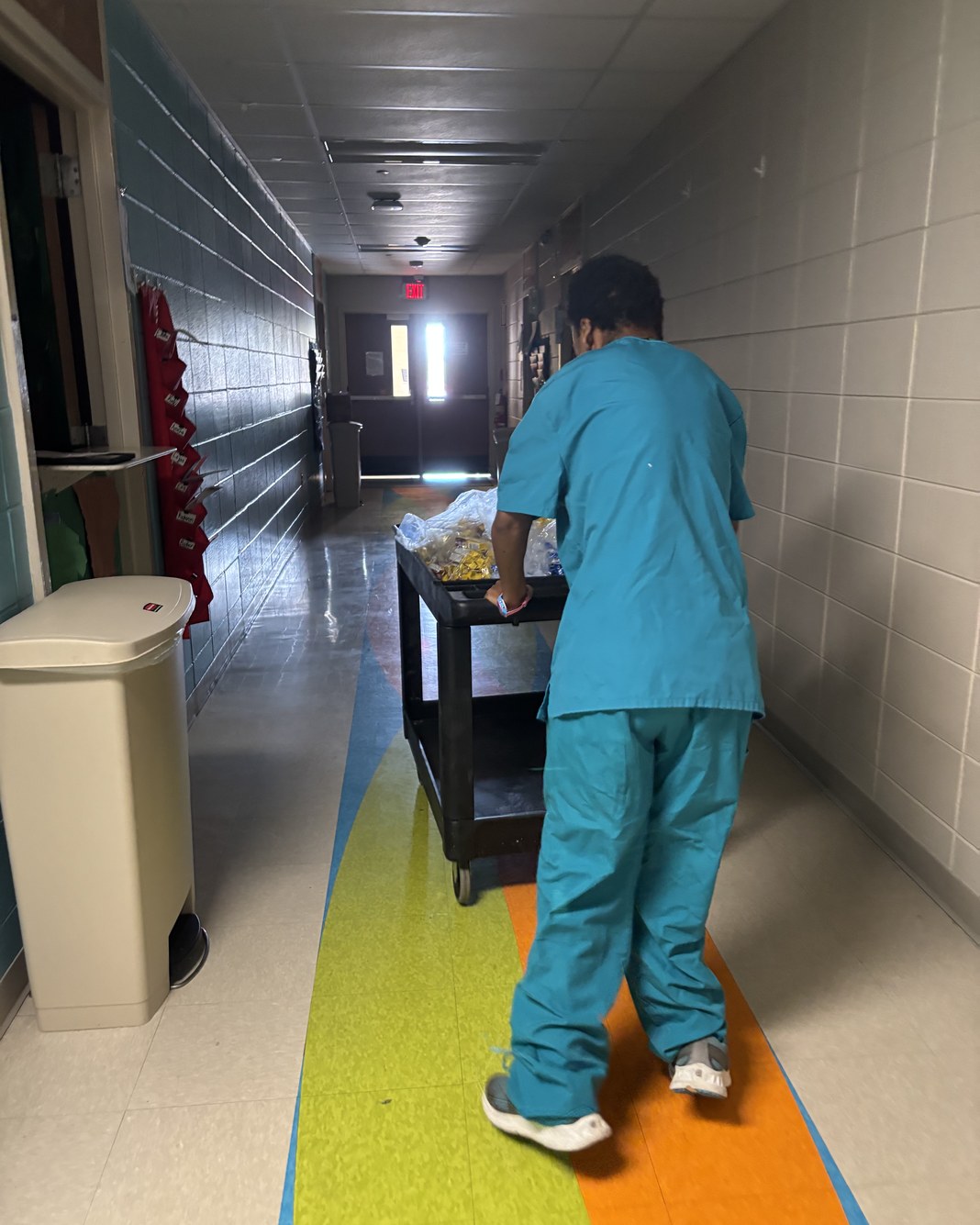 Miss T in scrubs pushing a supply cart at Arkansas Children's Hospital